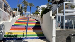 Una escalera con peldaños de colores del arcoíris que llevan a un edificio.