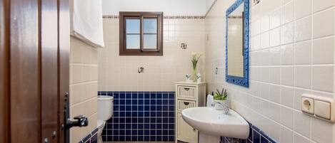 Een badkamer met toilet, wastafel en spiegel.