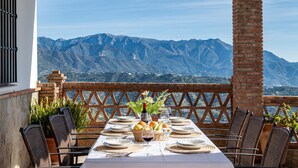 A table set for dining with a mountain view, wicker chairs, and a brick column. - Casa Baena by At Home Costa del sol (Torrox)