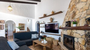 A living room with a stone fireplace, a flat-screen TV, and a sofa. - Casa Baena by At Home Costa del sol (Torrox)