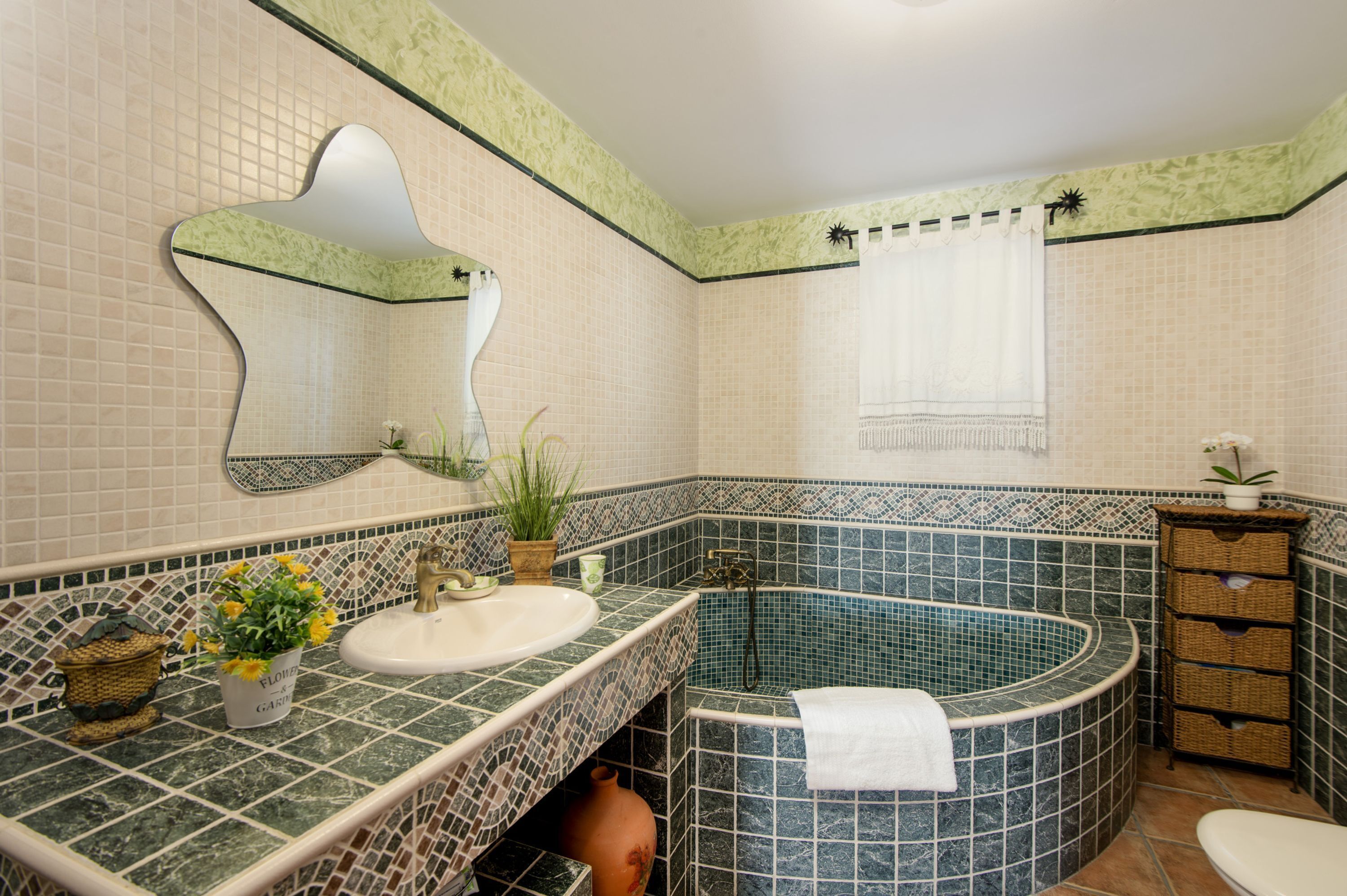 A bathroom with a freestanding bathtub, a sink with a mirror, and a vanity with wicker baskets.