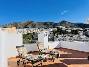 A terrace with two lounge chairs, a small table, and a potted plant. - Apartamento Mar de Nerja Sunset (Nerja)