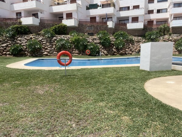 Ein Schwimmbecken, umgeben von einer Steinmauer, mit einem Rettungsring und einem Verbotsschild für Schwimmer.