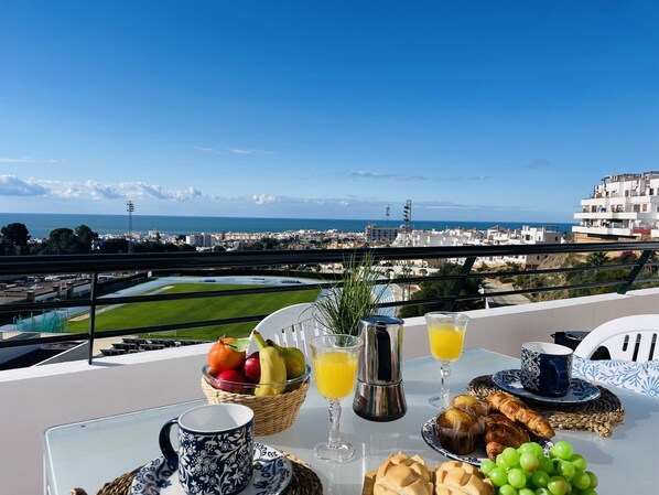 Un balcone con un tavolo apparecchiato per la colazione, con vista sulla città costiera.