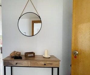 Una consola de madera con un espejo, una vela y una caja con la etiqueta 'HOME'.