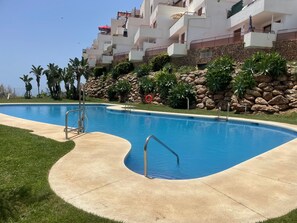 Una piscina con una parete in pietra e palme.