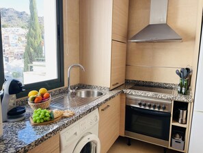 Eine moderne Küche mit Spüle aus Edelstahl, einer Arbeitsplatte aus Granit, einem Einbauofen und einer Waschmaschine.