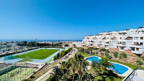 Zona residencial con edificios blancos modernos, un campo deportivo y una piscina.