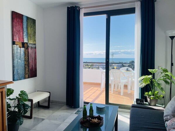 Una sala de estar moderna con un amplio ventanal corredero que da a una terraza exterior.