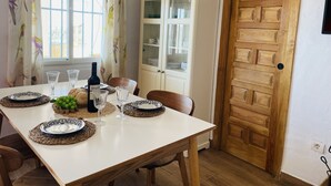 A dining area with a white table set for four, including plates, glasses, and a bottle of wine. - Cortijo Montesue os con Vistas by At Home Costa de (Torrox)