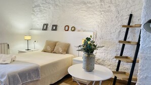 A bedroom with a bed, bedside table, lamp, and a small round table with a plant. - Cortijo Montesue os con Vistas by At Home Costa de (Torrox)
