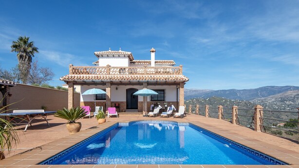 A swimming pool with a view of mountains, a patio with lounge chairs, and a building with a tiled roof. - Casa Ascen by At Home Costa del Sol (Torrox)