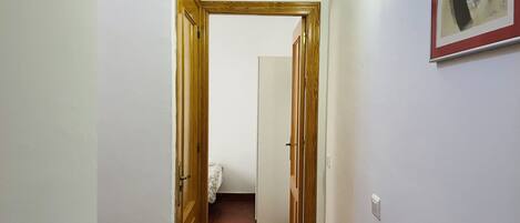 Un pasillo con puertas de madera y una pared blanca con un cuadro abstracto enmarcado.