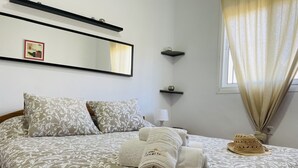 A neatly made bed with patterned bedding, a folded towel, a small decorative item, and a wall-mounted shelf. - Cortijo Mira con Piscina Privada by At Home Costa (Torrox)