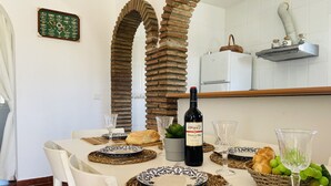 A dining table set with plates, glasses, a bottle of wine, bread, and a basket of grapes. - Cortijo Mira con Piscina Privada by At Home Costa (Torrox)