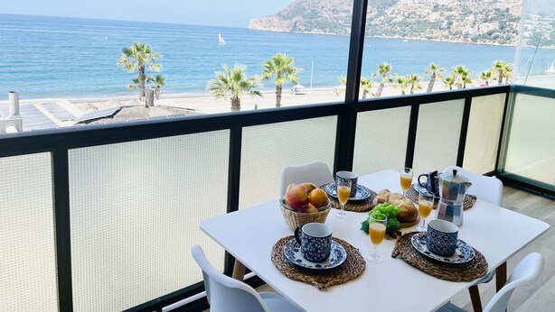Un balcon avec une table dressée pour le petit-déjeuner, donnant sur une plage.