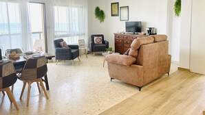 Un salon moderne avec un canapé, des fauteuils, une table basse et un téléviseur.