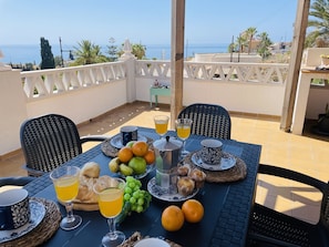 A table set for breakfast with fruits, pastries, and drinks, overlooking a scenic view of the sea. - Casa Blanca con Vistas al mar by At Home Costa del (Torrox)