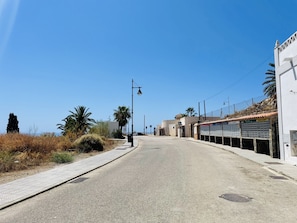 A quiet street with a sidewalk, street lamps, and a building with a tiled roof. - Casa Blanca con Vistas al mar by At Home Costa del (Torrox)