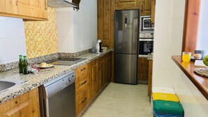 Una cocina con armarios de madera, un refrigerador de acero inoxidable, lavavajillas y salpicadero de azulejos.