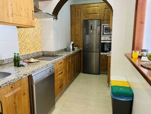 A kitchen with wooden cabinets, a stainless steel refrigerator, a dishwasher, and a tiled backsplash. - Casa Blanca con Vistas al mar by At Home Costa del (Torrox)