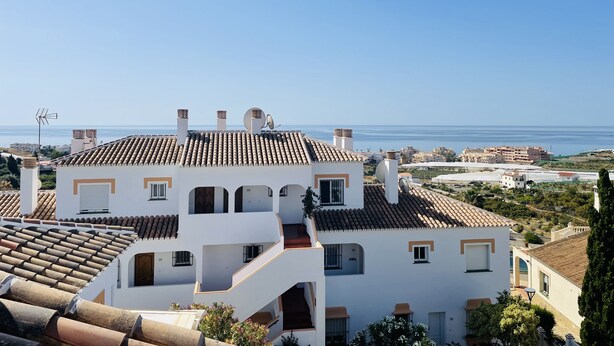 A coastal residential area with terracotta-tiled roofs, white walls, and multiple chimneys. - Apartamento Torrox Park Sunset View (Torrox)