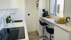Et moderne køkken med en marmor bordplade, kaffemaskine og et vindue med udsigt.