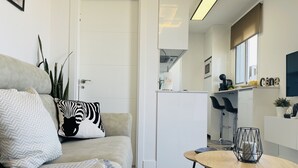 En moderne stue med sofa, sofabord og et køkken i baggrunden.