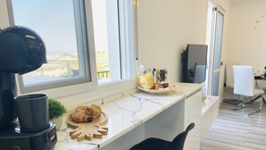 Et moderne køkken med en marmor bordplade, en kaffemaskine, en croissant og en lille potteplante.