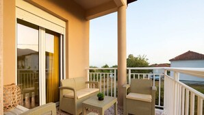 A balcony with wicker furniture, a small table, and a potted plant. - Valira Stathmos Home, Rustic Charm Cottage w Views (Valira)