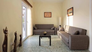 A living room with a sofa, a coffee table, and three wooden cat figures. - Valira Stathmos Home, Rustic Charm Cottage w Views (Valira)