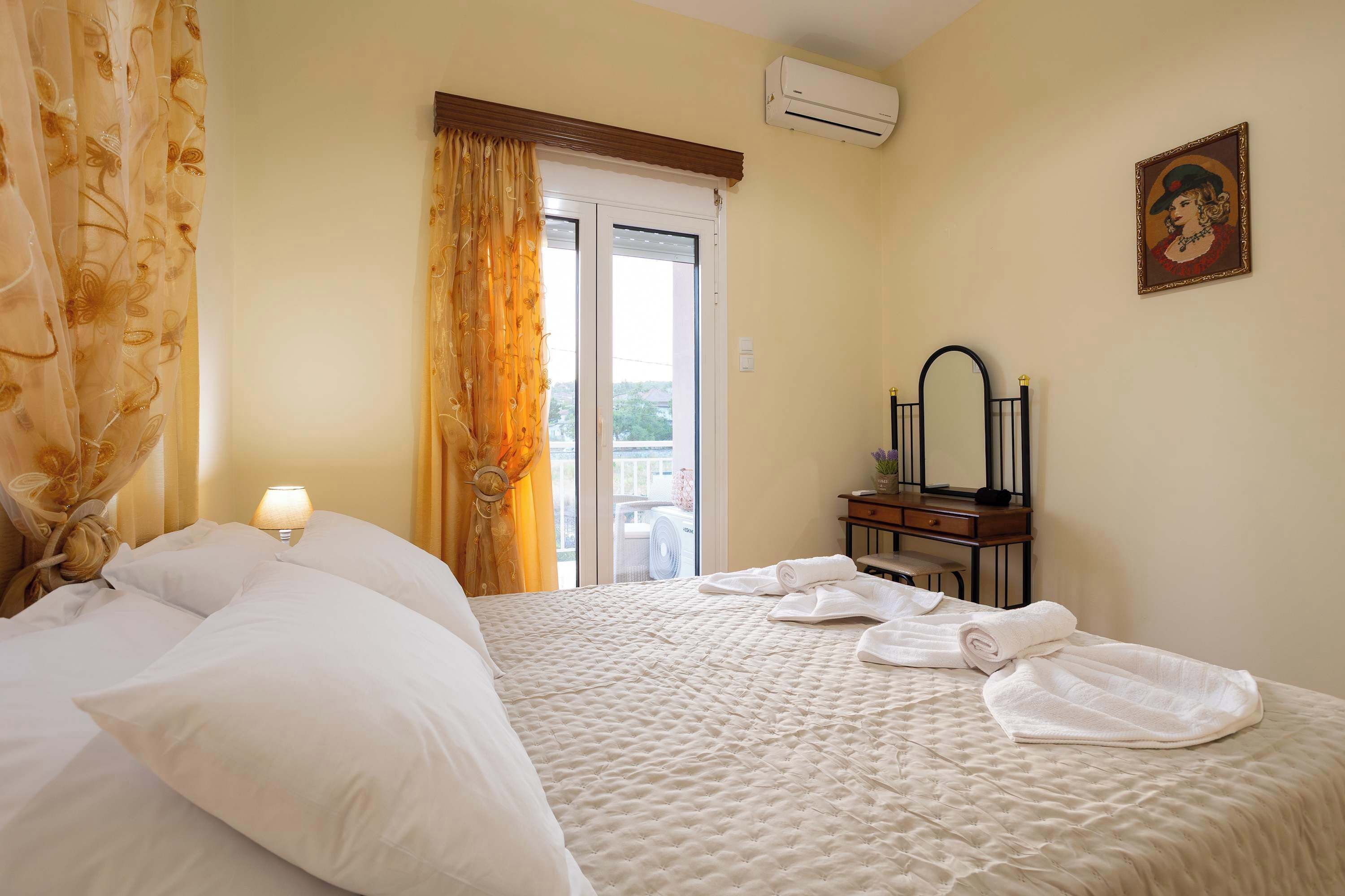 A hotel room with a bed, a nightstand with a lamp, a dresser, a mirror, and a painting on the wall.