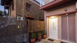 A stone building with a wooden fence, a white door, and potted plants. - Valira Stathmos Home, Rustic Charm Cottage w Views (Valira)
