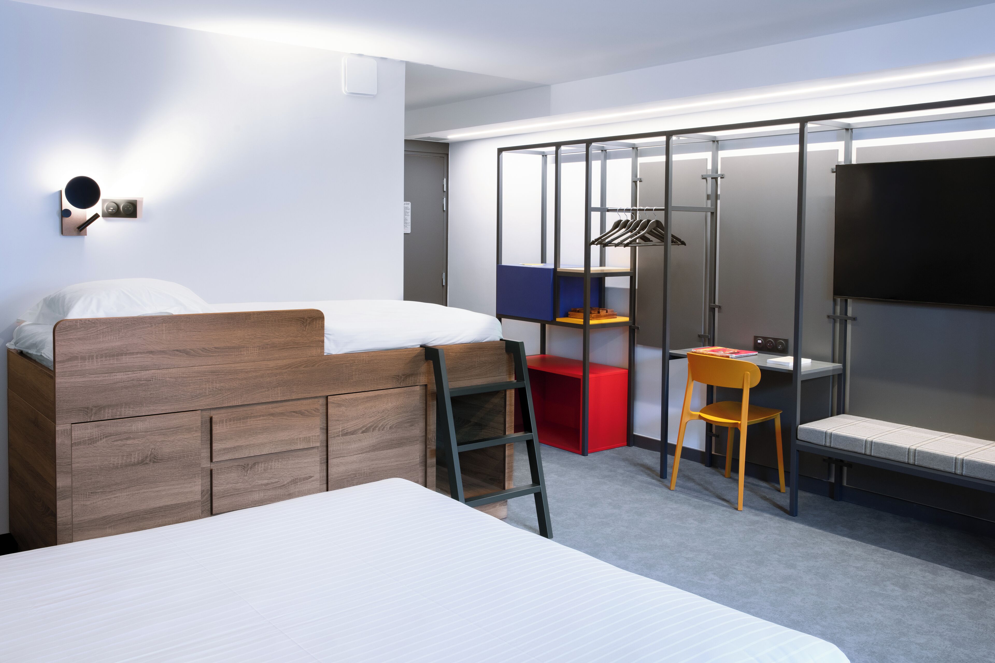 A bedroom with a wooden bed, a desk, a chair, and a wardrobe with a mirror.