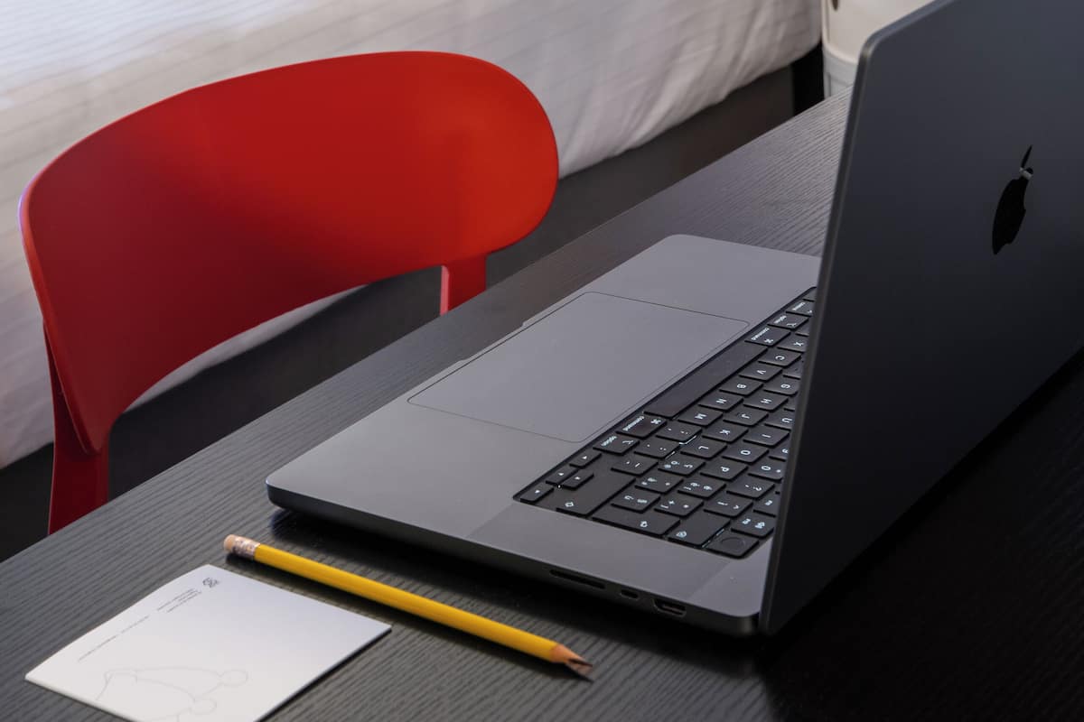 Een hotelkamer met een bed, een rode stoel, een laptop en een muurschildering.