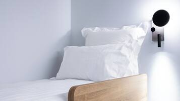 A single bed with a wooden headboard and white bedding in a room with light blue walls.