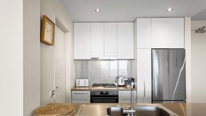 A modern kitchen with white cabinets, stainless steel appliances, and a built-in oven. - Ocean Views, 2 Bedroom Apartment (San Remo)