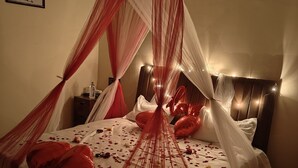 A bed with a canopy, balloons, and rose petals. - Sky View Resort (Bhuj)