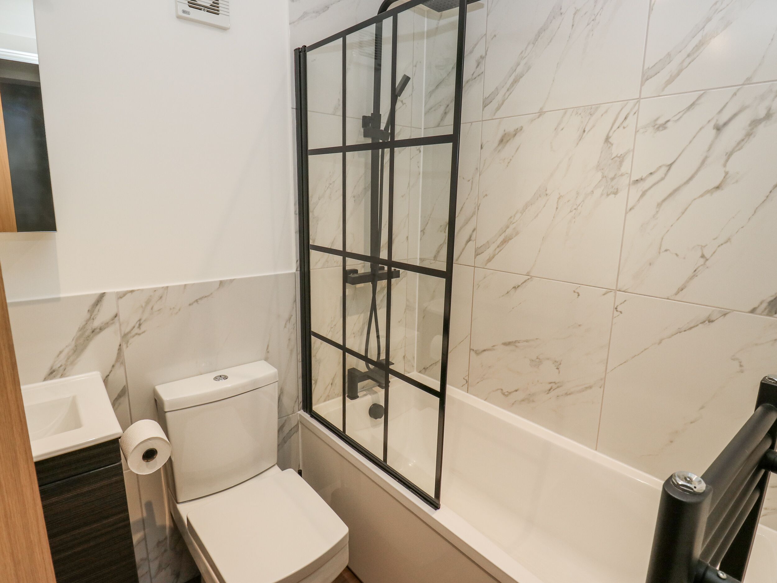 Un bagno con il water, una doccia vetrata e piastrelle in marmo.