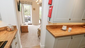 A modern kitchen with wooden countertops, a built-in oven, and a view to a balcony. - Millside View (Keighley)
