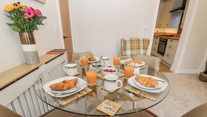 A breakfast table with croissants, juice, and a vase of flowers. - Millside View (Keighley)