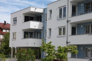 A multi-story residential building with balconies, windows, and a clear sky.