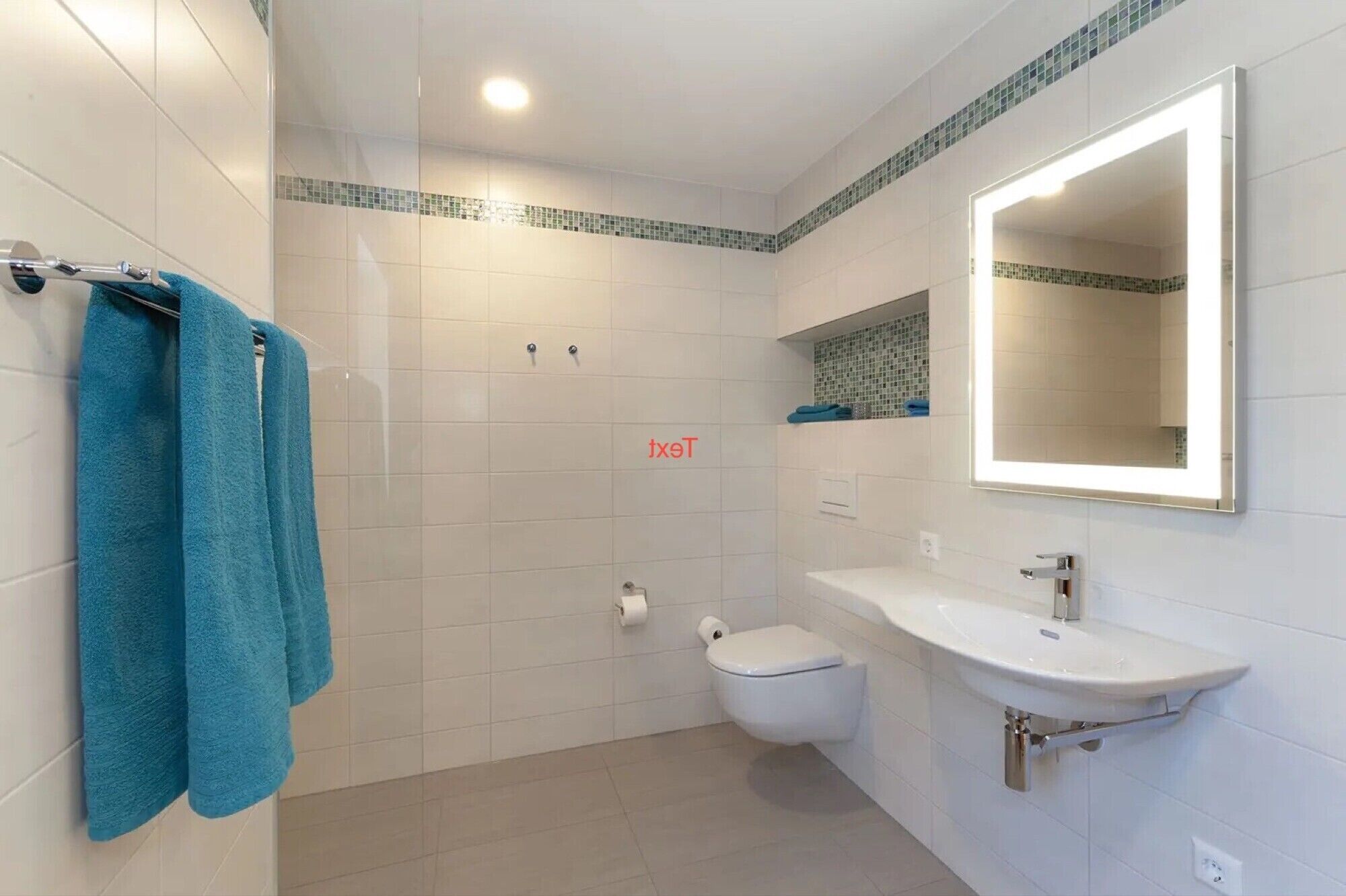 Un bagno con il water, un lavandino e uno specchio con luce.