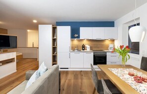 Une cuisine moderne avec des meubles blancs, un plan de travail en bois et un coin repas avec une table dressée pour deux personnes.