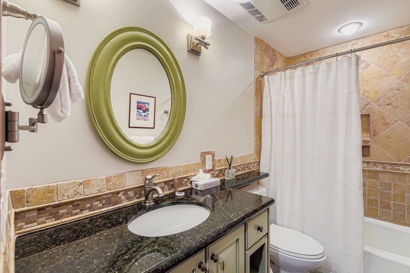 A bathroom with a sink, two mirrors, a toilet, and a shower curtain.