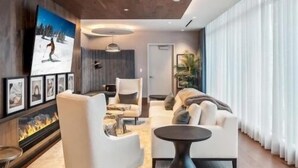 A modern living room with a fireplace, comfortable seating, and a large window with curtains.