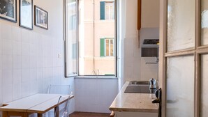 A compact kitchen with a window, a sink, and a dining area with a table and chairs. - Rental in Rome Casa Assunta (Rome)