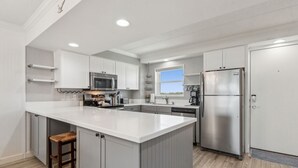 Una cocina moderna con muebles blancos, electrodomésticos de acero inoxidable y una isla grande.