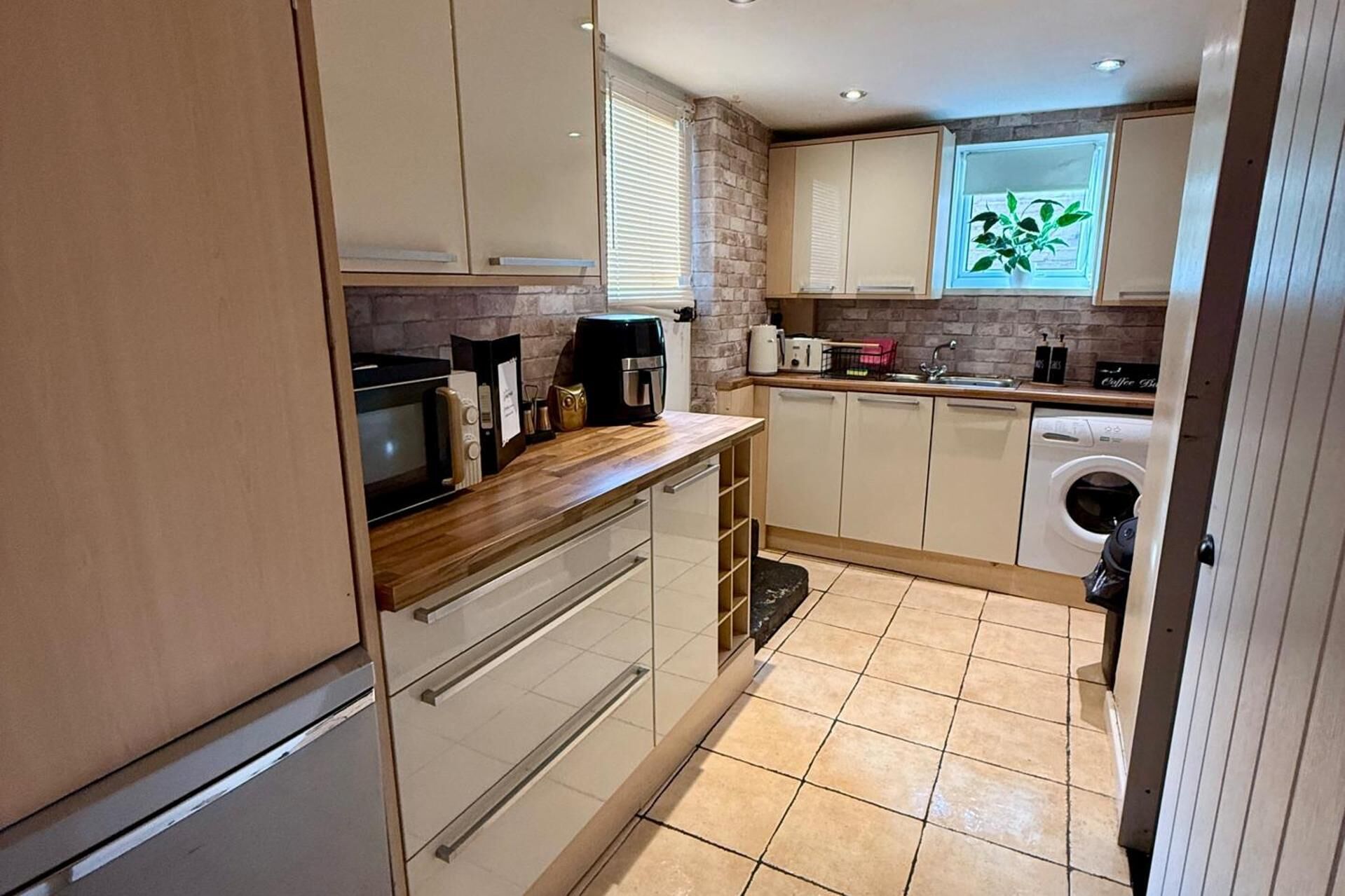 A compact kitchen with a microwave, coffee maker, and a washing machine.