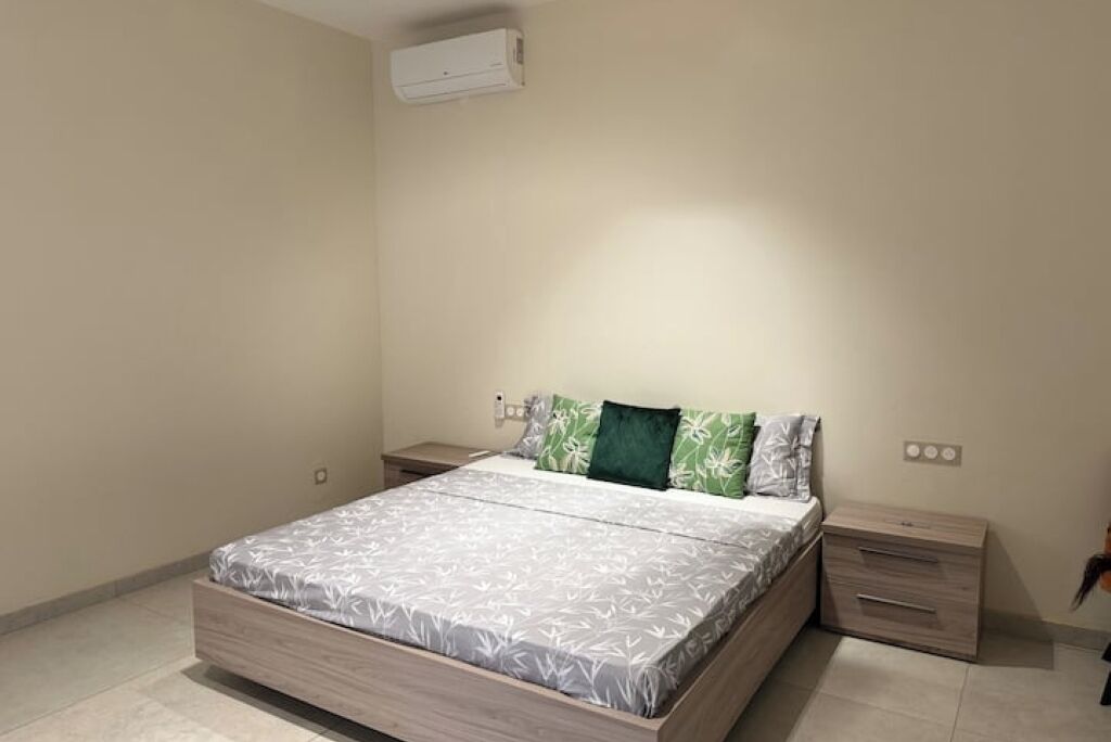 A bedroom with a bed, nightstands, and an air conditioning unit.